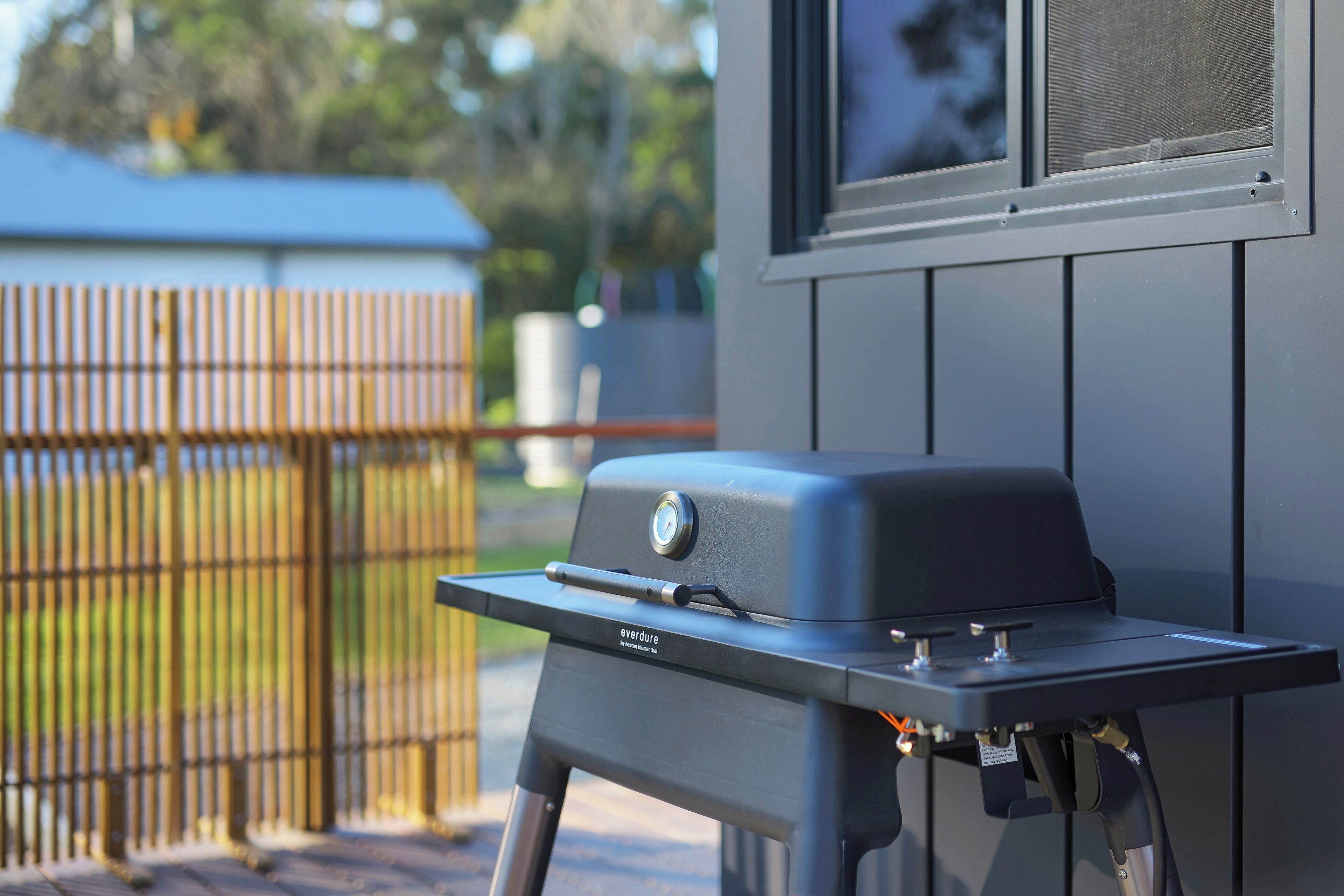 A portable barbecue grill with a control knob and a label, placed on a flat surface outdoors.