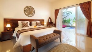 Ein Schlafzimmer mit einem großen Bett, einer Bank, einem Nachttisch, einer Lampe und Blick auf einen Pool durch eine Glastür.