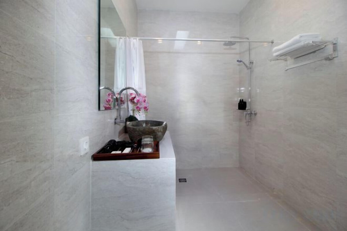 Een moderne badkamer met een grote spiegel, een wastafel, een douche en een handdoekrek.