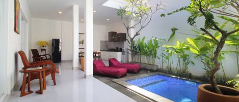 A modern interior with a pool, seating, and a kitchen area.