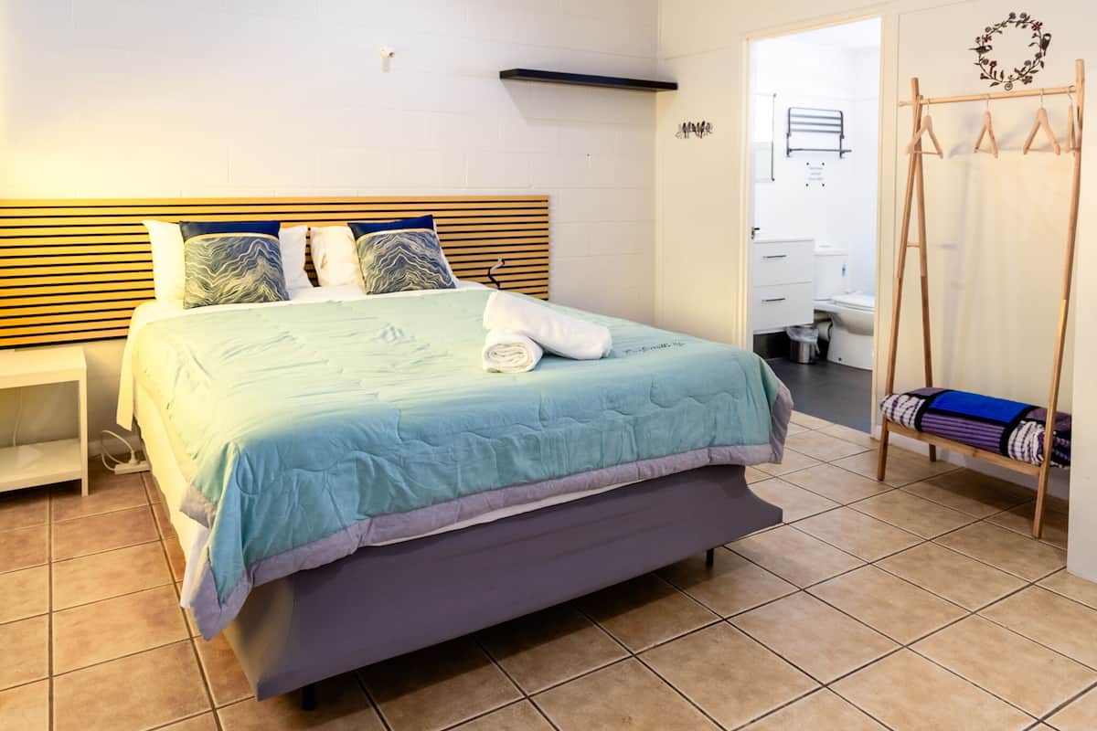 A neatly made bed with a blue and white bedspread, a wooden headboard, and a white nightstand to the left.