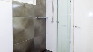 Una ducha con puerta de cristal y estante de metal.