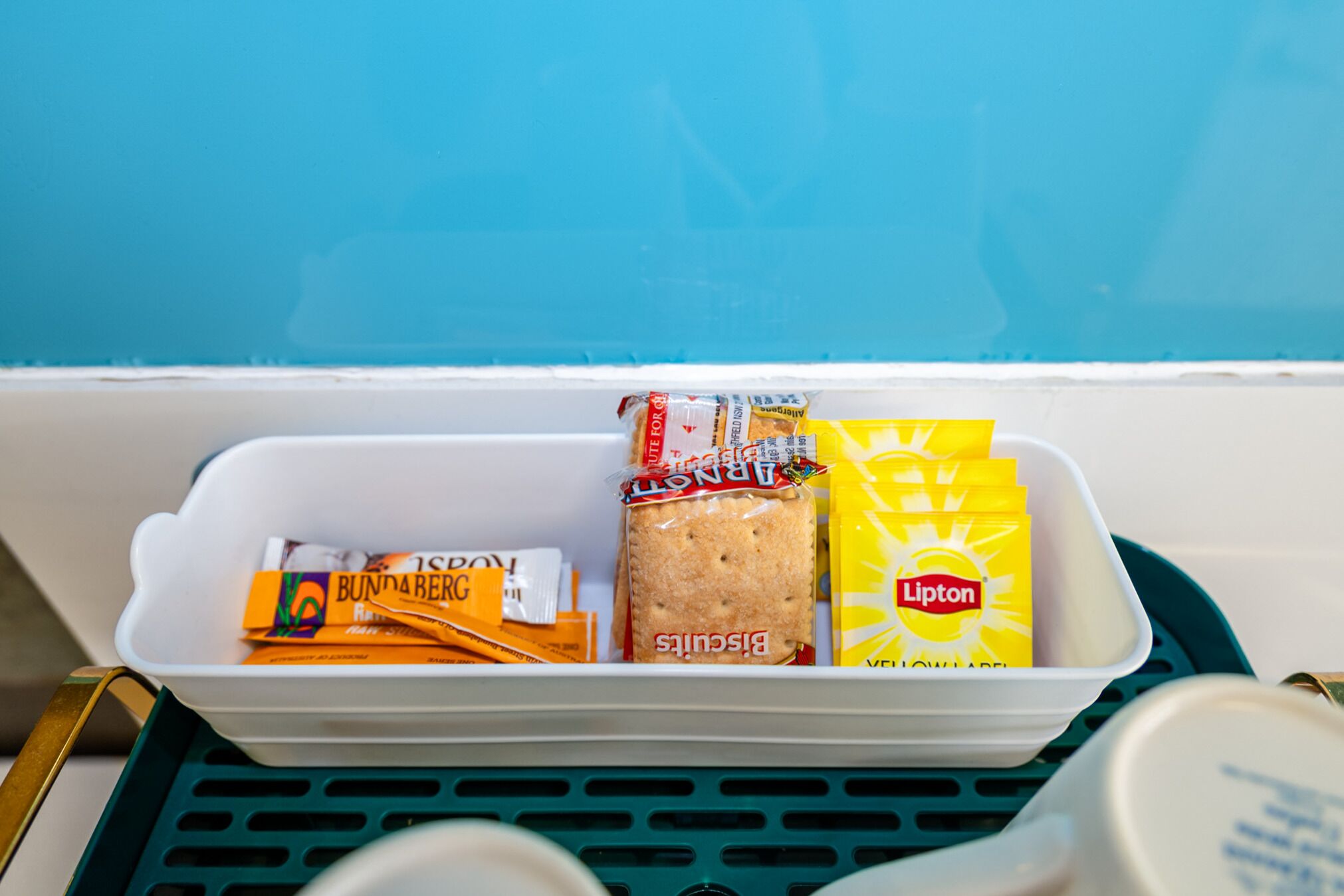 Een opbergbak met etenswaren, waaronder koekjes, Lipton thee en Bunda brood.