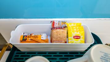 A storage bin with food items including biscuits, Lipton tea, and Bunda bread.