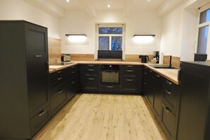 A modern kitchen with black cabinets, a wooden countertop, and a window above the sink. - Holiday Home 'Dat Rode Huus' with Private Terrace, Private Garden and Wi-Fi (Oesterwurth)