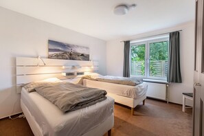 A bedroom with two beds, a window with curtains, a radiator, and a wall-mounted picture. - Holiday Home 'Ferienhaus Sprante' with Private Terrace, Private Garden and Wi-Fi (Brunsbüttel)