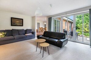 Ein modernes Wohnzimmer mit einem schwarzen Ledersofa, einem grauen Sofa und zwei runden Holztischen.