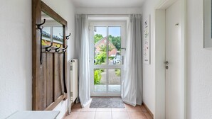 A hallway with a wooden door, a glass door leading outside, and a white wall with a framed sign. - Holiday Home 'Ferienhaus Sprante' with Private Terrace, Private Garden and Wi-Fi (Brunsbüttel)