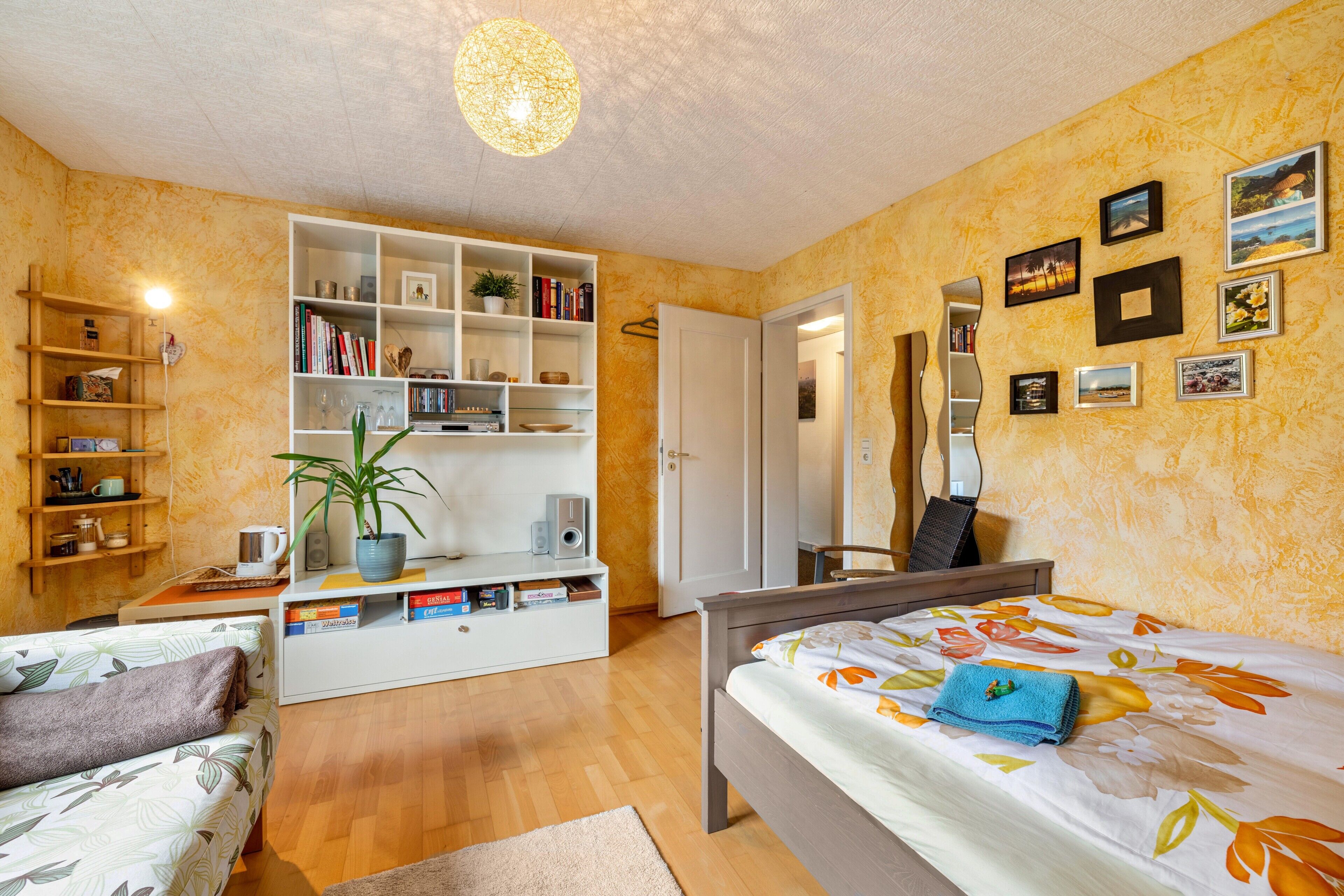 A bedroom with a bed, a desk, a bookshelf, and a wardrobe.