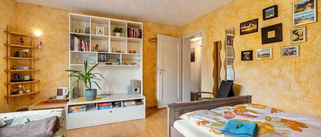 A bedroom with a bed, a desk, a bookshelf, and a wardrobe.