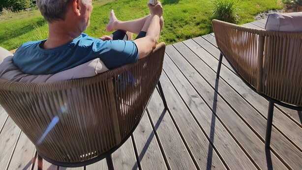 A person relaxing on a wooden deck with a scenic view of a forested valley. - Apartment 'Am Stadtwald' with Mountain View, Private Terrace and Wi-Fi (Triberg)