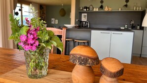 A wooden table with a glass vase of flowers and two wooden mushroom-shaped objects. - Apartment 'Am Stadtwald' with Mountain View, Private Terrace and Wi-Fi (Triberg)