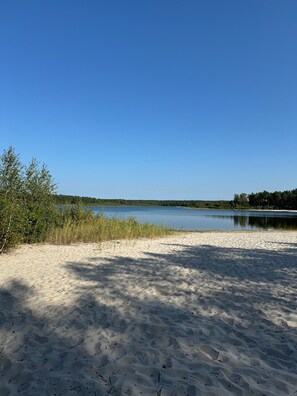 Une plage de sable fin, un ciel bleu azur et un lac paisible.