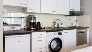 A compact kitchen with a washing machine, a coffee maker, and a built-in oven. - Apartment in 'St. Pauli' Hotel with Wi-Fi (Hamburg)