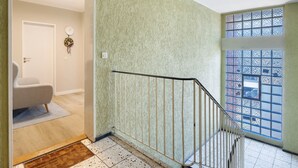 A staircase with a metal railing, a door with a wall clock, and a window with a grid pattern. - Apartment in 'St. Pauli' Hotel with Wi-Fi (Hamburg)