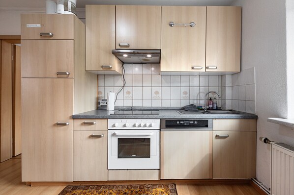 Une cuisine avec des meubles de couleur bois clair, une cuisinière blanche et un lave-vaisselle.