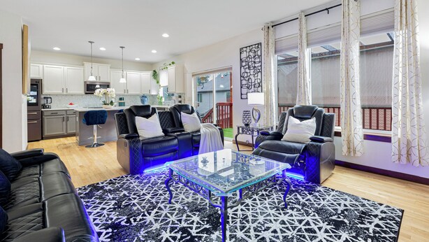A modern living room with a glass coffee table, two black leather sofas, and a patterned rug. - Sunrise Villa: Solar panels, updated (Bothell)