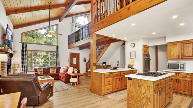 A spacious living area with a large wooden staircase, a kitchen with wooden cabinets, and a cozy seating area with a fireplace.