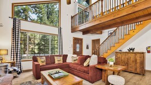 A spacious living room with a red sectional sofa, wooden coffee table, and a staircase leading to an upper level.