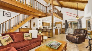 A spacious living area with a wooden staircase, leather sofa, and a dining area.