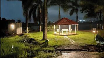 A gazebo with a red roof, surrounded by palm trees and a paved path.
