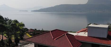 Zona residencial costera con casas de techo rojo y vistas despejadas al mar y montañas a lo lejos.