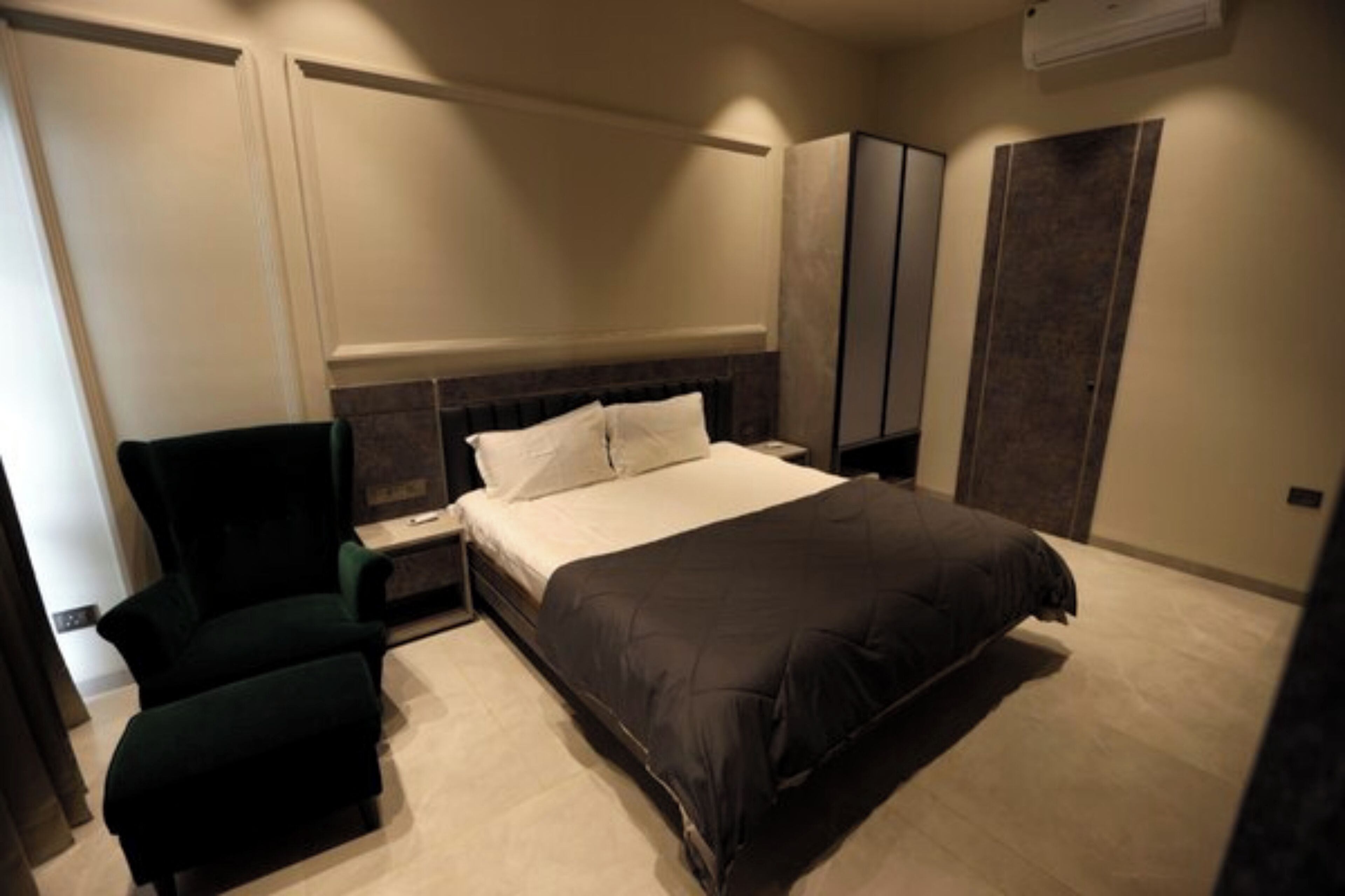 Ein Schlafzimmer mit einem großen Bett, einem Nachttisch, einem Sessel und einem Kleiderschrank.