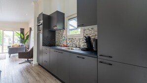 Una cucina moderna con mobili grigi, una cappa aspirante nera e una finestra sopra il lavello.