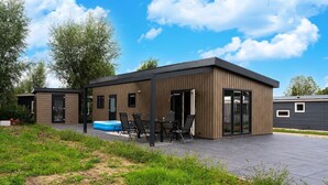 Un edificio moderno con patio, piscina e zona relax coperta.
