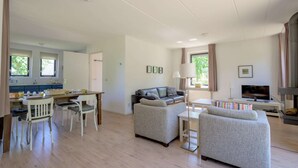 A spacious living area with a dining table, two sofas, a TV, and a fireplace. - Bungalow in Sondel near Slotermeer Lake (Sondel)