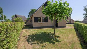 A residential house with a sloped roof, a front door, and a small front yard with a tree. - Bungalow in Sondel near Slotermeer Lake (Sondel)