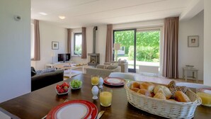 A dining area with a table set for breakfast, including fruits, bread, and juice. - Bungalow in Sondel near Slotermeer Lake (Sondel)