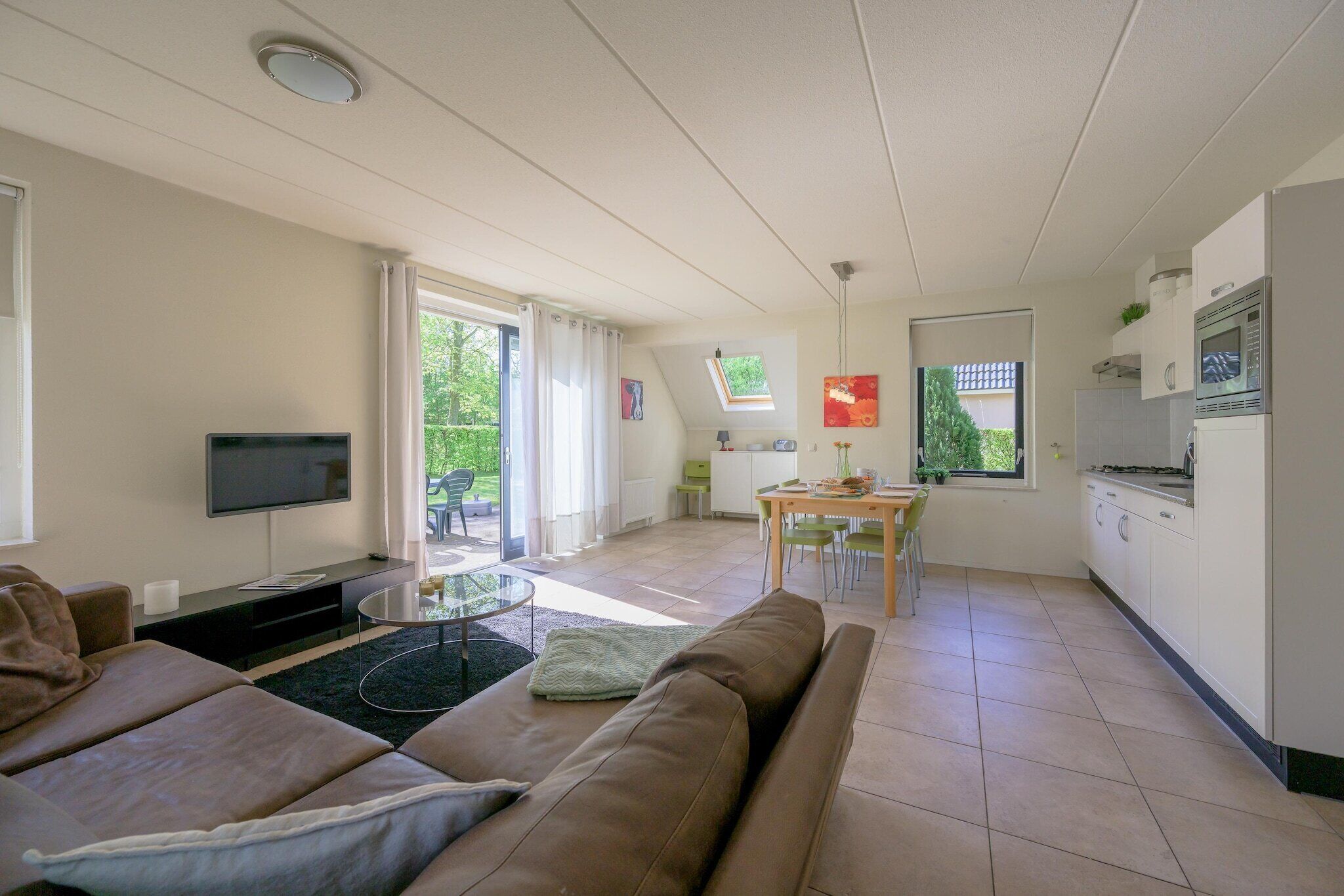 A modern living room with a sofa, TV, and a dining area with a table and chairs.