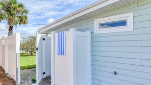 Une maison blanche avec une petite dépendance attenante, comprenant deux toilettes portables et une serviette accrochée à la porte.