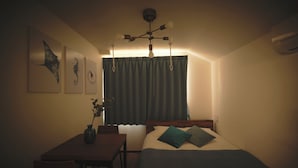 Ein Schlafzimmer mit Bett, Schreibtisch, Stuhl, Deckenventilator und Bildern an der Wand.