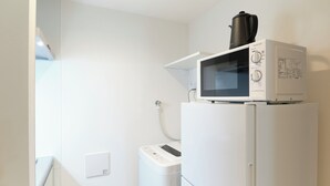 A kitchen with a microwave on top of a refrigerator, a washing machine, and a water heater. - Fuente Nishi Sugamo by Tranova (Tokyo)