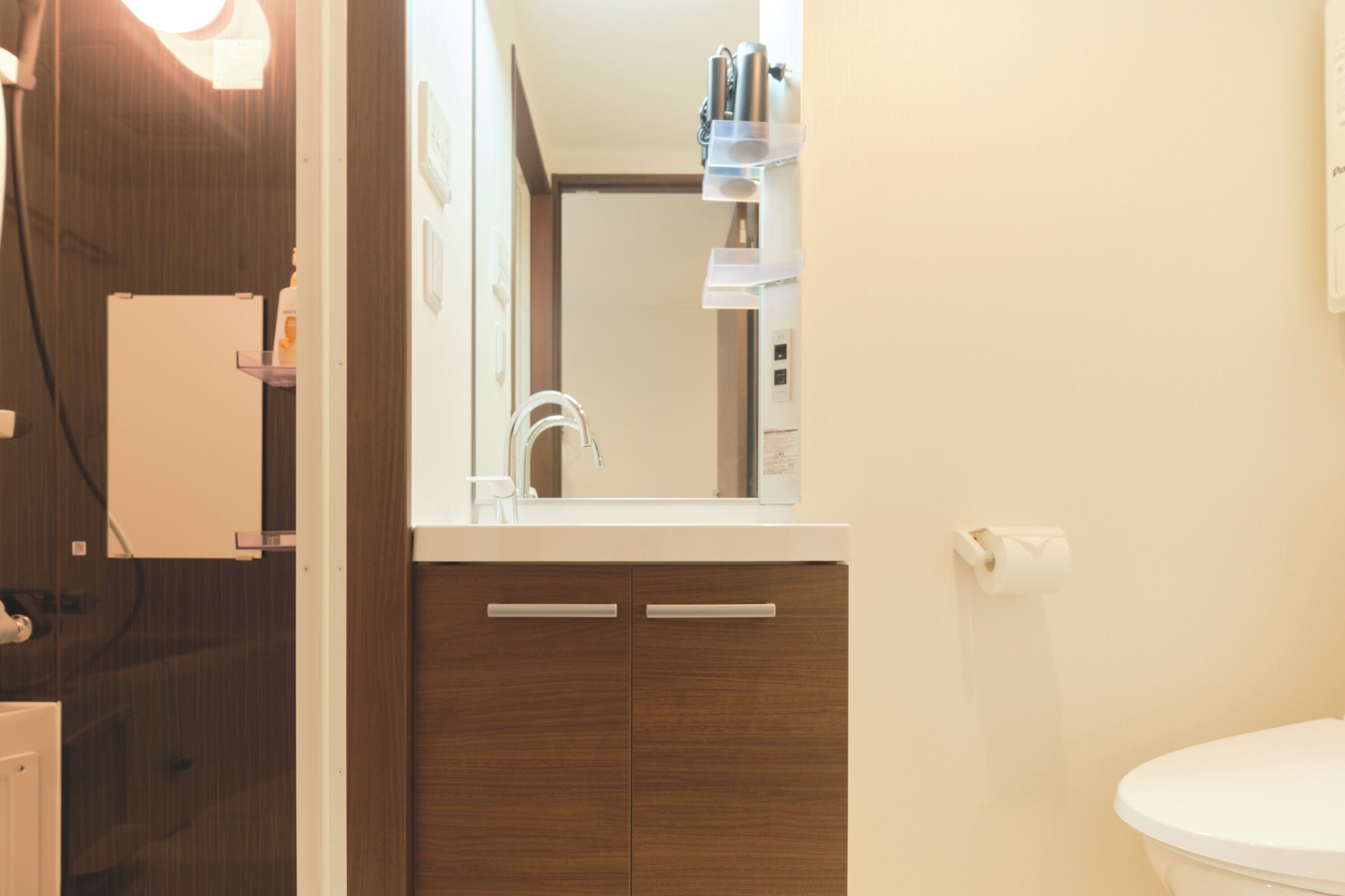 A bathroom with a white toilet, wooden cabinets, a mirror, and a shelf with toiletries.