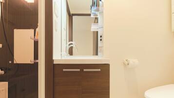 A bathroom with a white toilet, wooden cabinets, a mirror, and a shelf with toiletries.