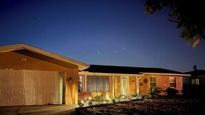 A residential house with a garage, a front porch, and a well-lit driveway. - The Blooming Sanctuary - 3br with pool and EV-Charger (Rotonda West)