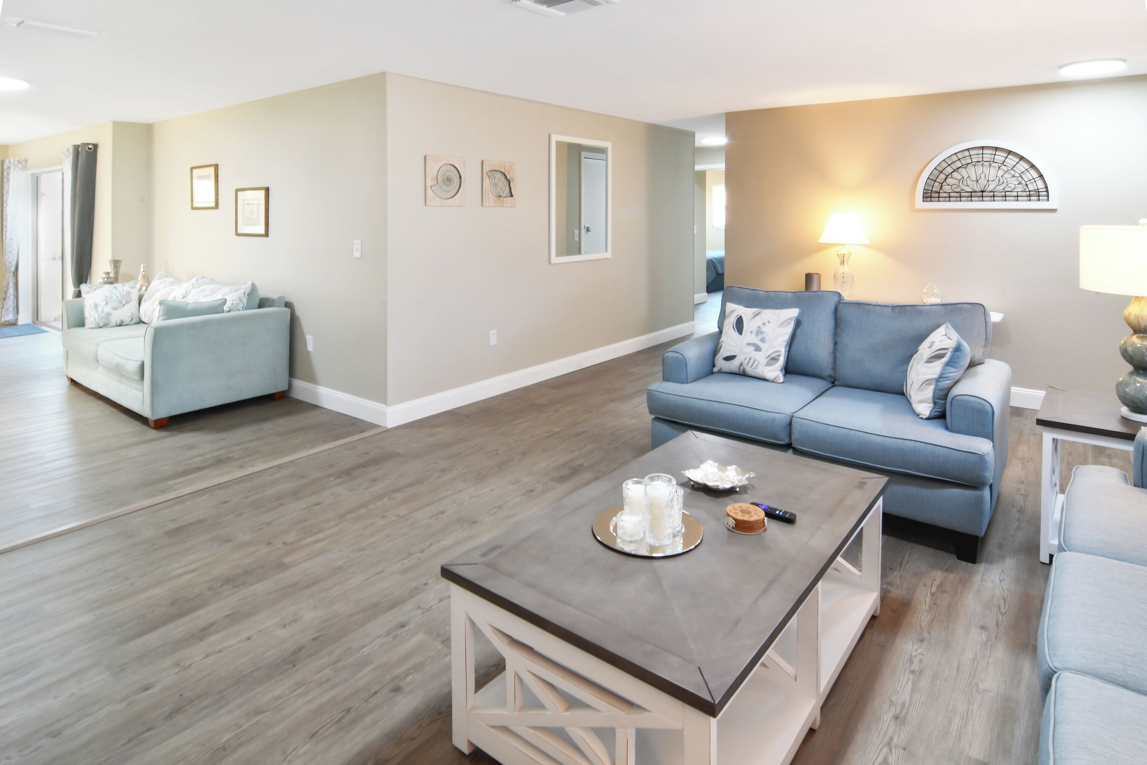 A spacious living room with a light blue sofa, a coffee table, and a wooden floor.