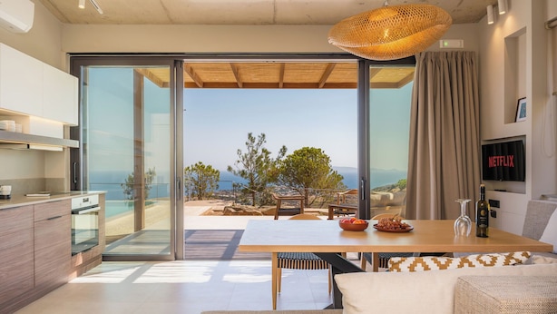 Eine moderne Küche mit Meerblick, ein Essbereich mit Tisch und Stühlen sowie eine gemütliche Sitzecke mit Sofa und Fernseher.