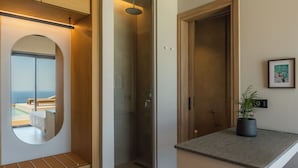 Ein modernes Badezimmer mit einer Glasdusche, einem runden Spiegel und Blick auf einen Balkon.
