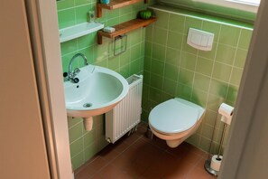 Ein Badezimmer mit Waschbecken, Toilette und einer Wand aus grünen Fliesen.