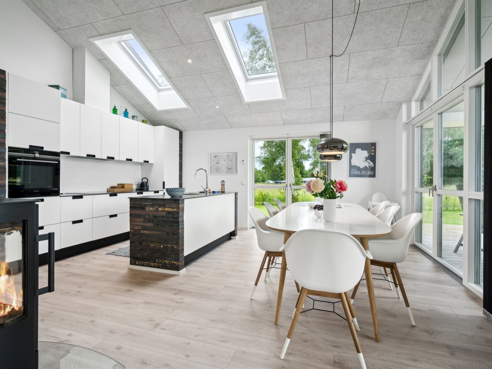 A modern kitchen with a central island, white cabinetry, and a dining area with a round table and white chairs.