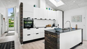 Une cuisine moderne avec des meubles blancs, un îlot central et une lucarne.