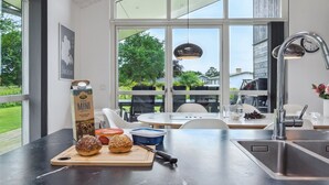 Une cuisine moderne avec une grande fenêtre, une planche à découper avec du pain et un emballage de lait.