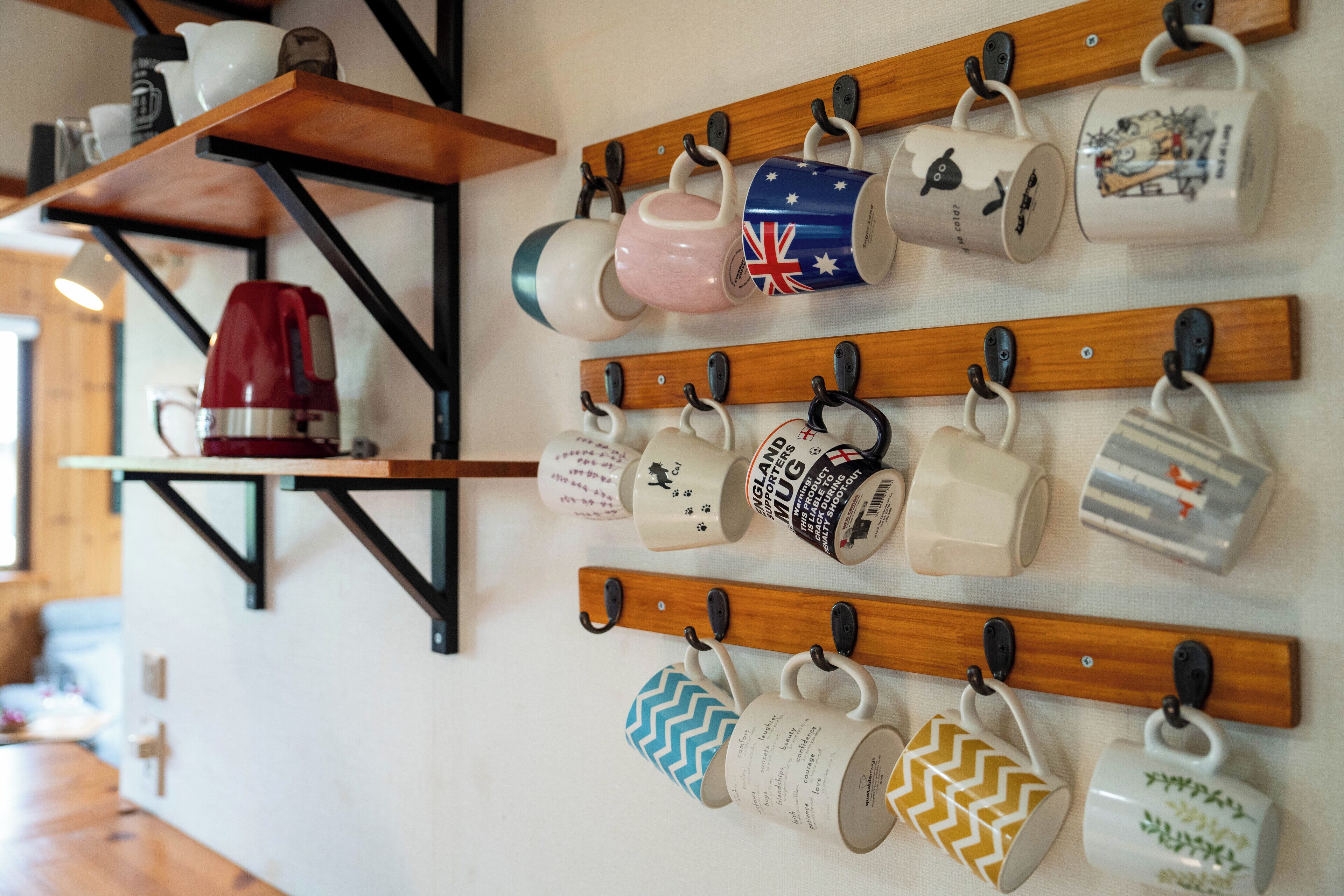 Une collection de tasses aux motifs et aux dessins variés, exposées sur deux étagères en bois fixées au mur.