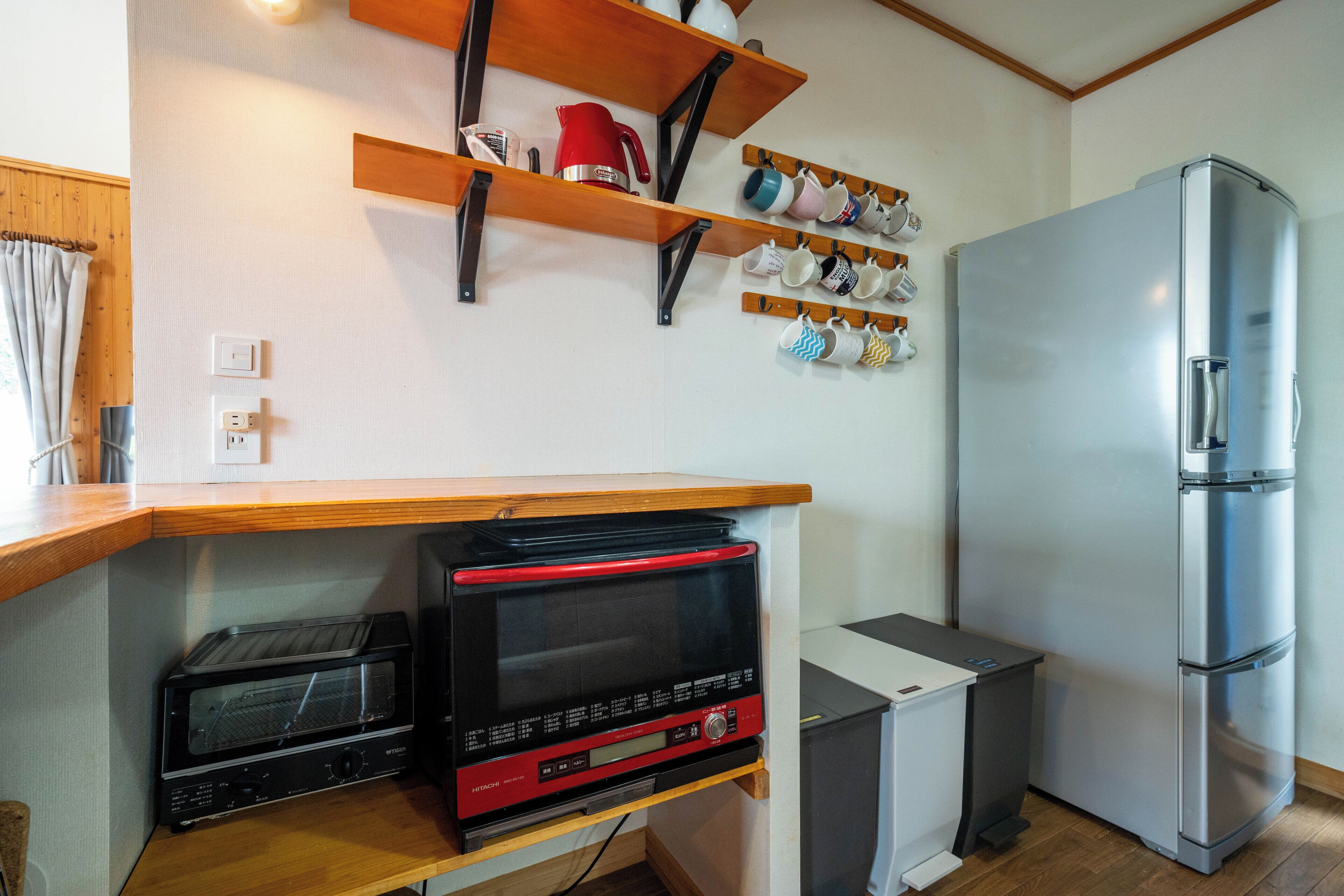 Una cucina compatta con forno integrato, frigorifero e macchina del caffè su un ripiano.