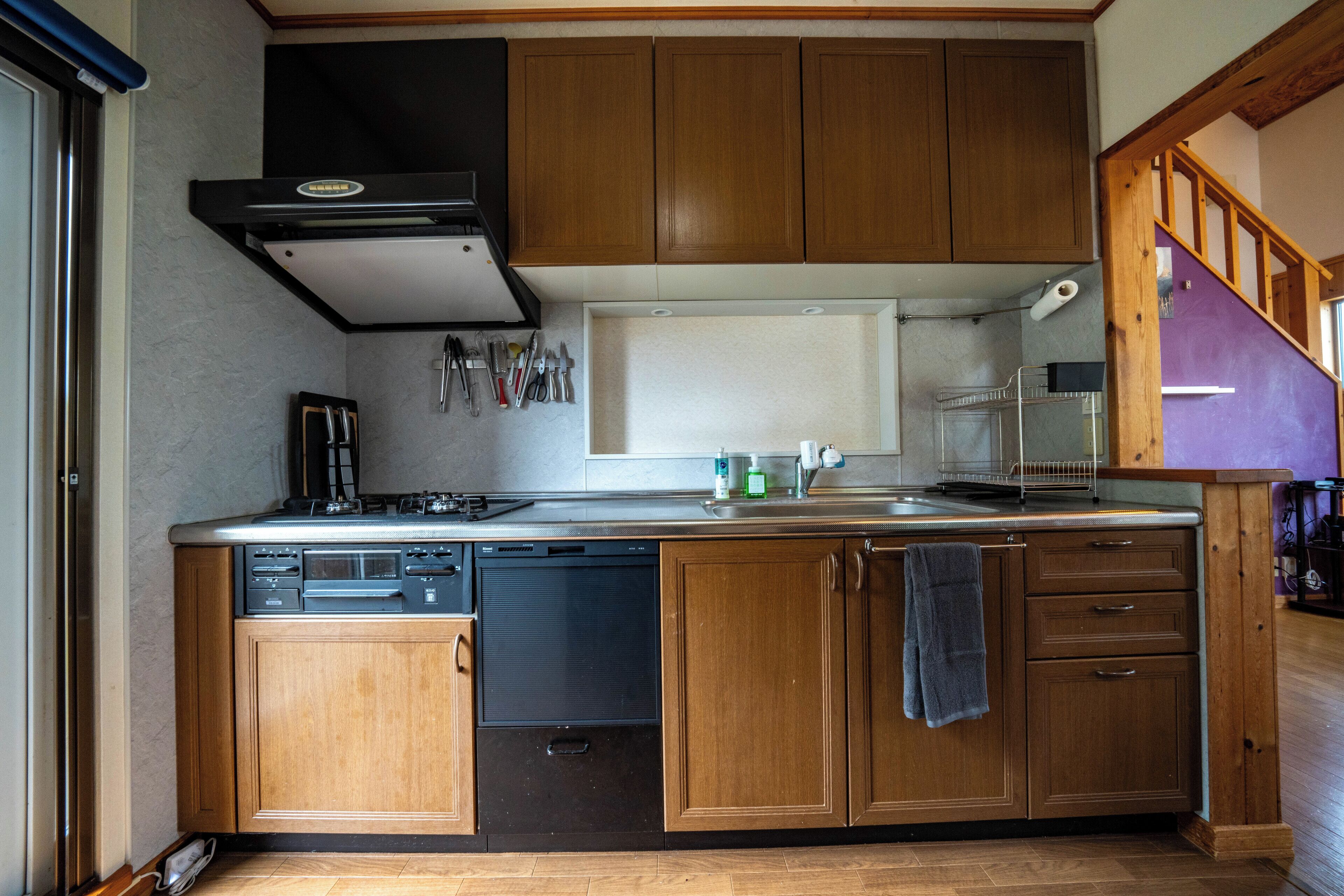 A kitchen with wooden cabinets, a dishwasher, a stove, and a window above the sink.