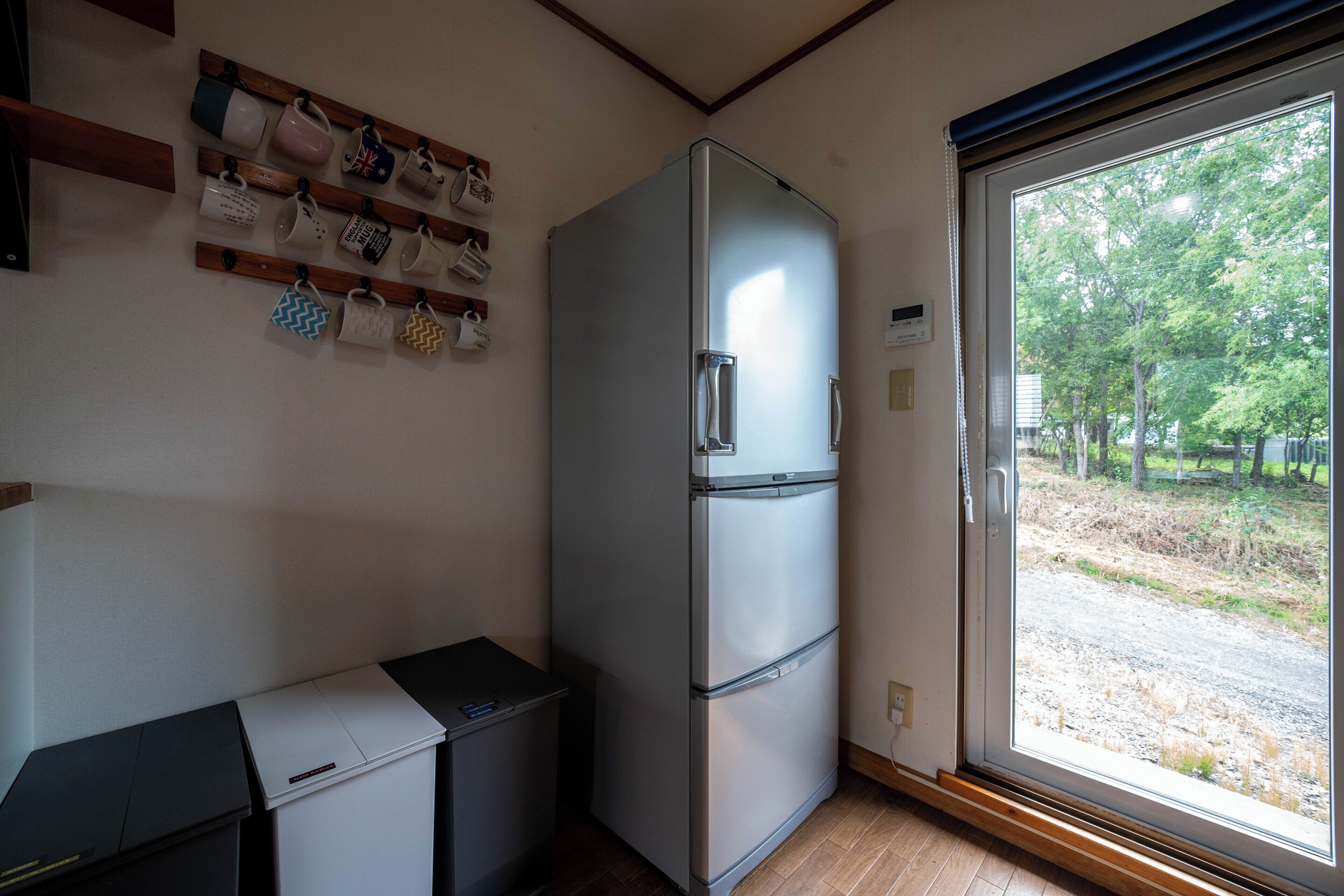 A compact kitchen with a built-in refrigerator, a small countertop, and a window with a view of trees.